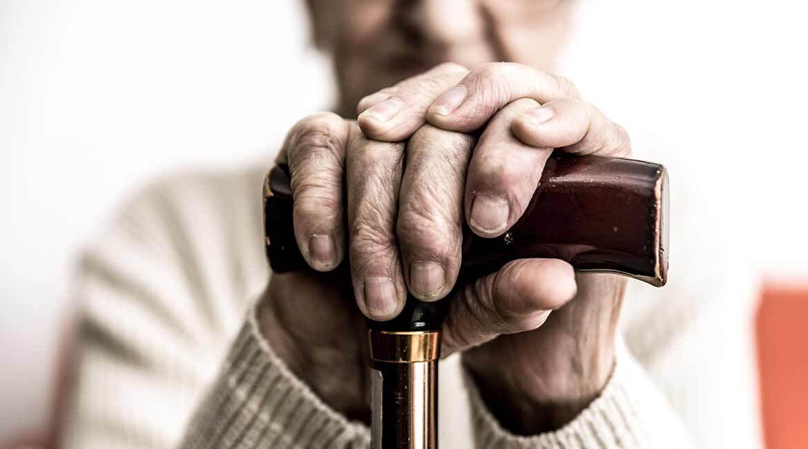 Mains âgées tenant fermement une canne, symbolisant le soutien et la stabilité.