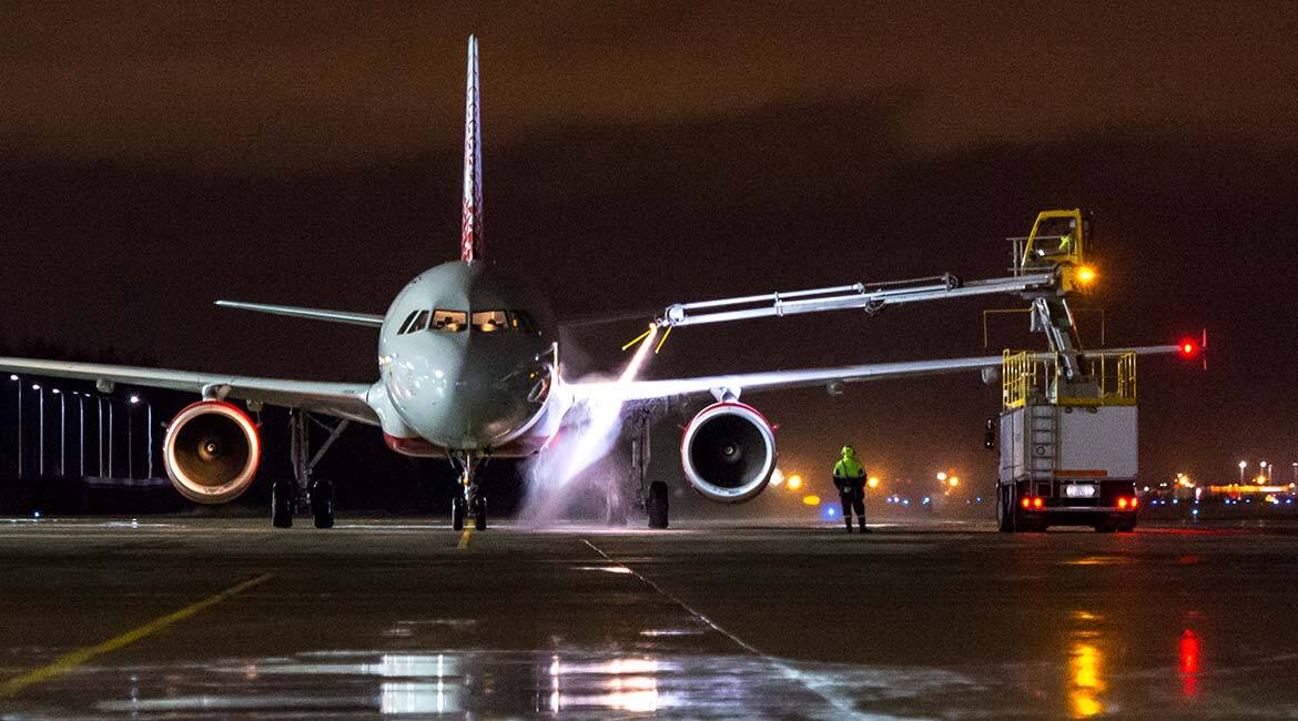 Aircraft receiving de-icing treatment at nighttime on the tarmac.
