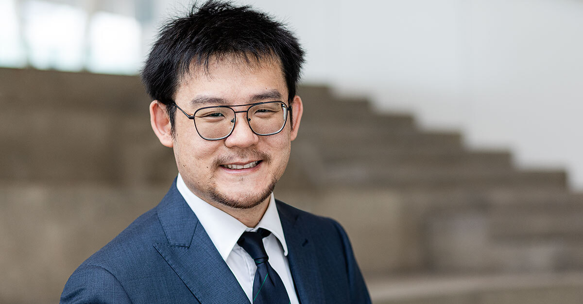 Confident professional smiling in a smart suit at a university setting.