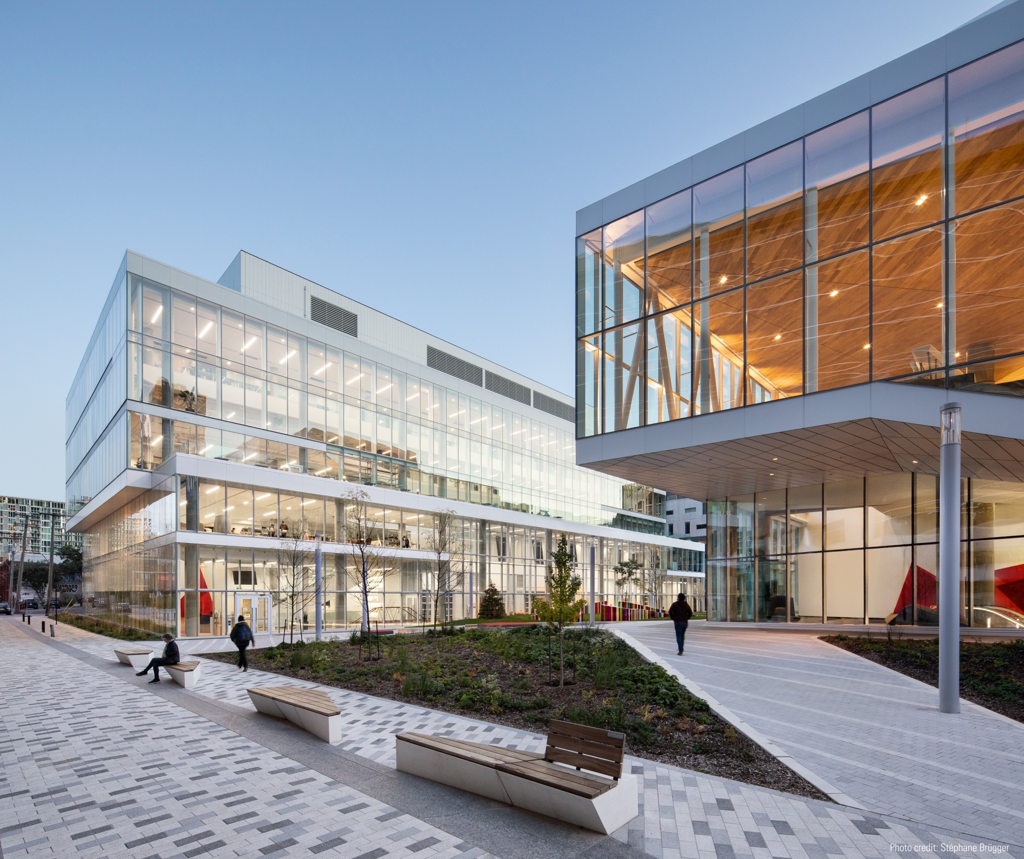 Modern university building with glass facade and outdoor seating area.