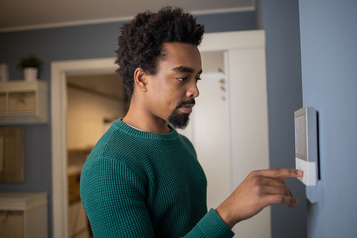 Student adjusting a smart thermostat for a sustainable environment.