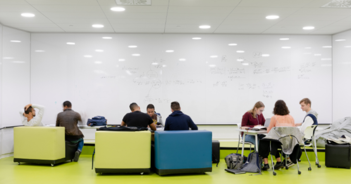 Étudiants travaillant en groupes dans une salle d'étude moderne.