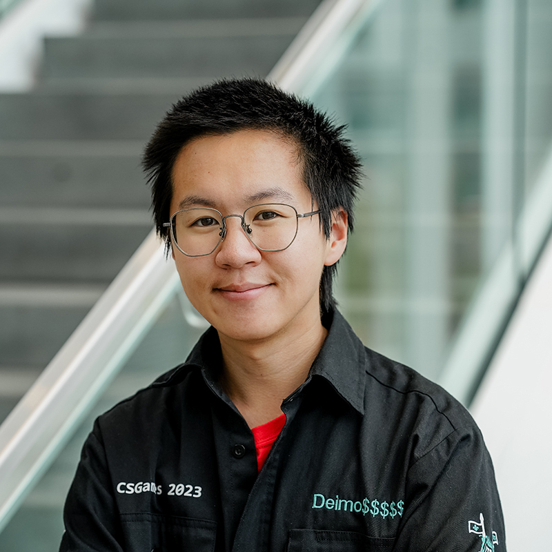 Étudiant souriant avec tenue professionnelle, lunettes, devant escalier.