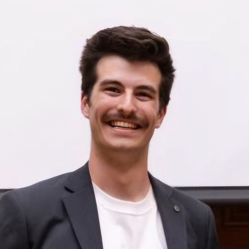 Jeune homme souriant en tenue décontractée avec un blazer.