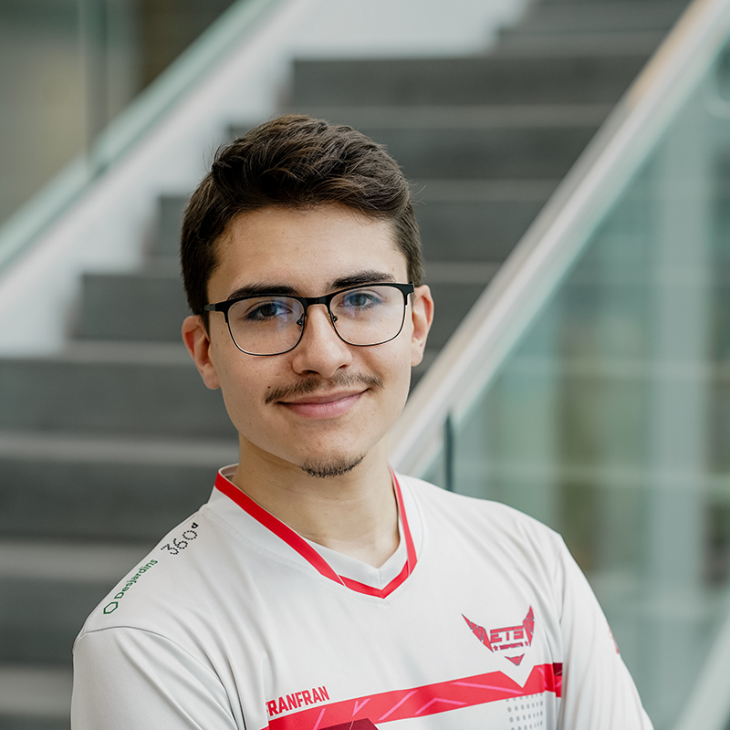 Jeune étudiant souriant en tenue d'e-sport, représentant l'esprit d'équipe et l'innovation.