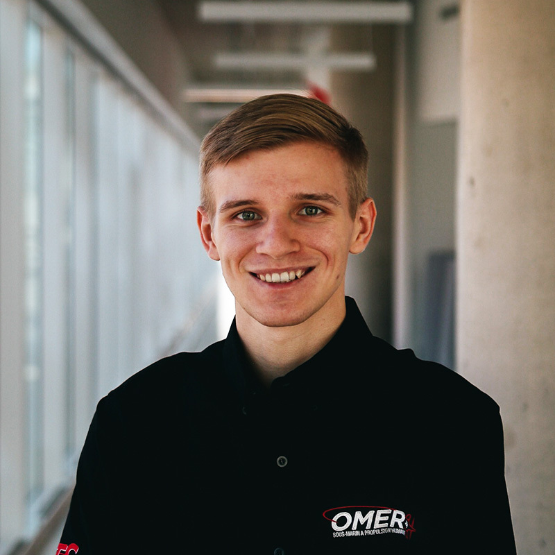 Étudiant souriant en tenue professionnelle, représentant un club universitaire en technologie.