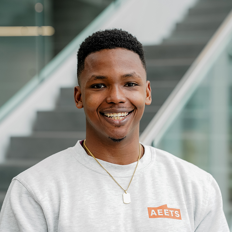 Étudiant souriant dans un cadre universitaire moderne.