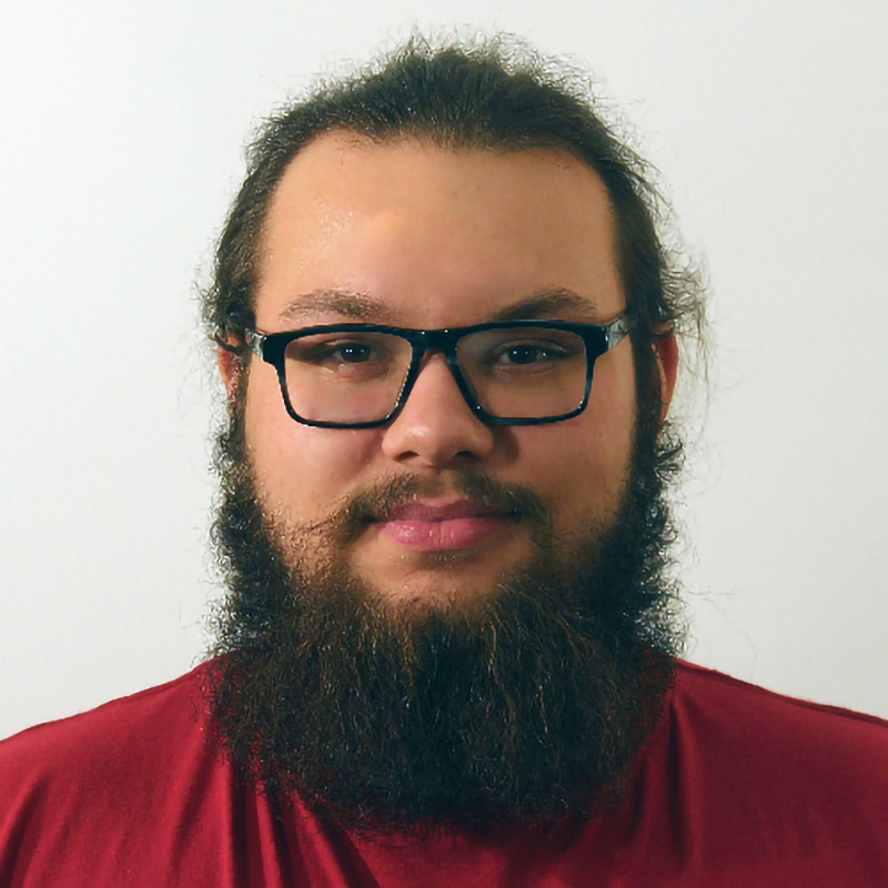 Étudiant sérieux avec lunettes et barbe fournie.