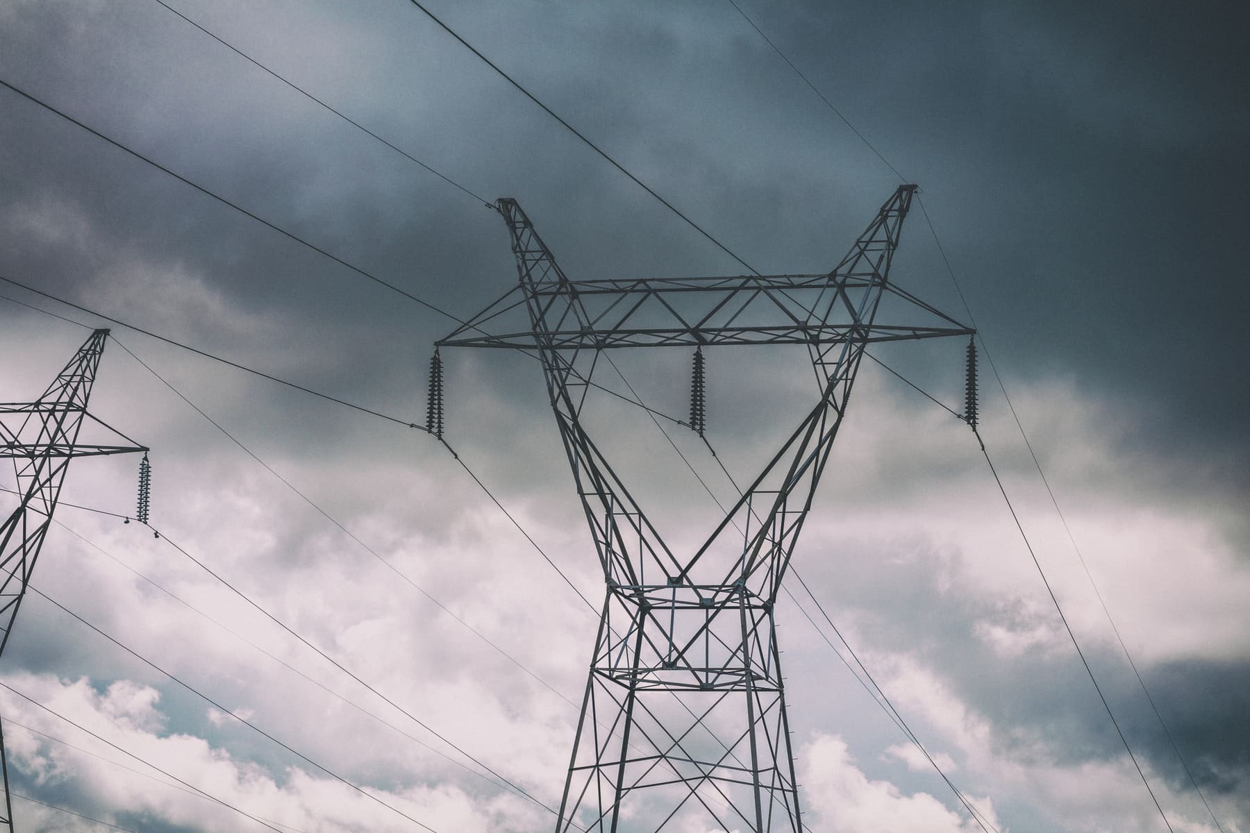 Power lines and towers against a cloudy sky, showcasing electrical engineering feats.