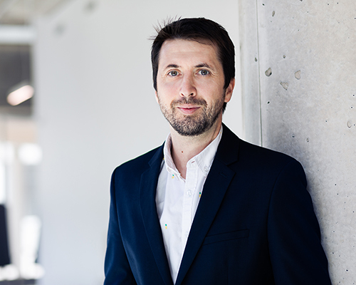 Confident professional in a suit standing in a modern office setting.