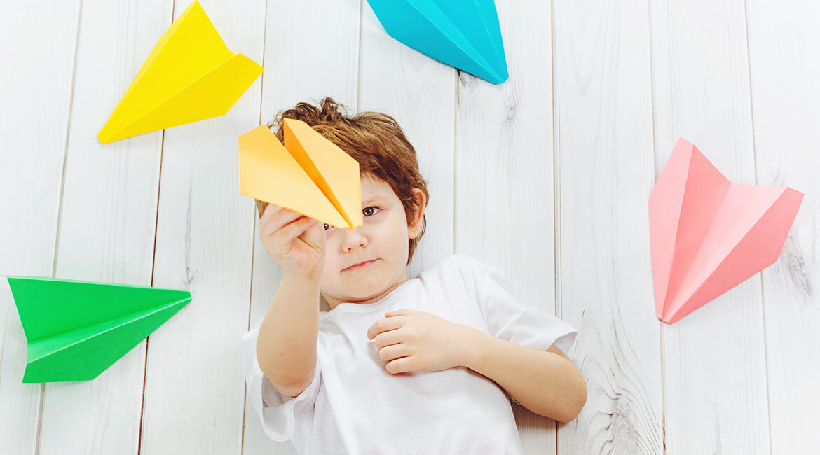 Child explores aerodynamics with colorful paper planes. Creativity meets science!