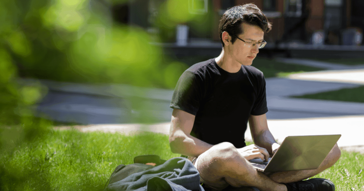 Focused student working outdoors on a university campus.