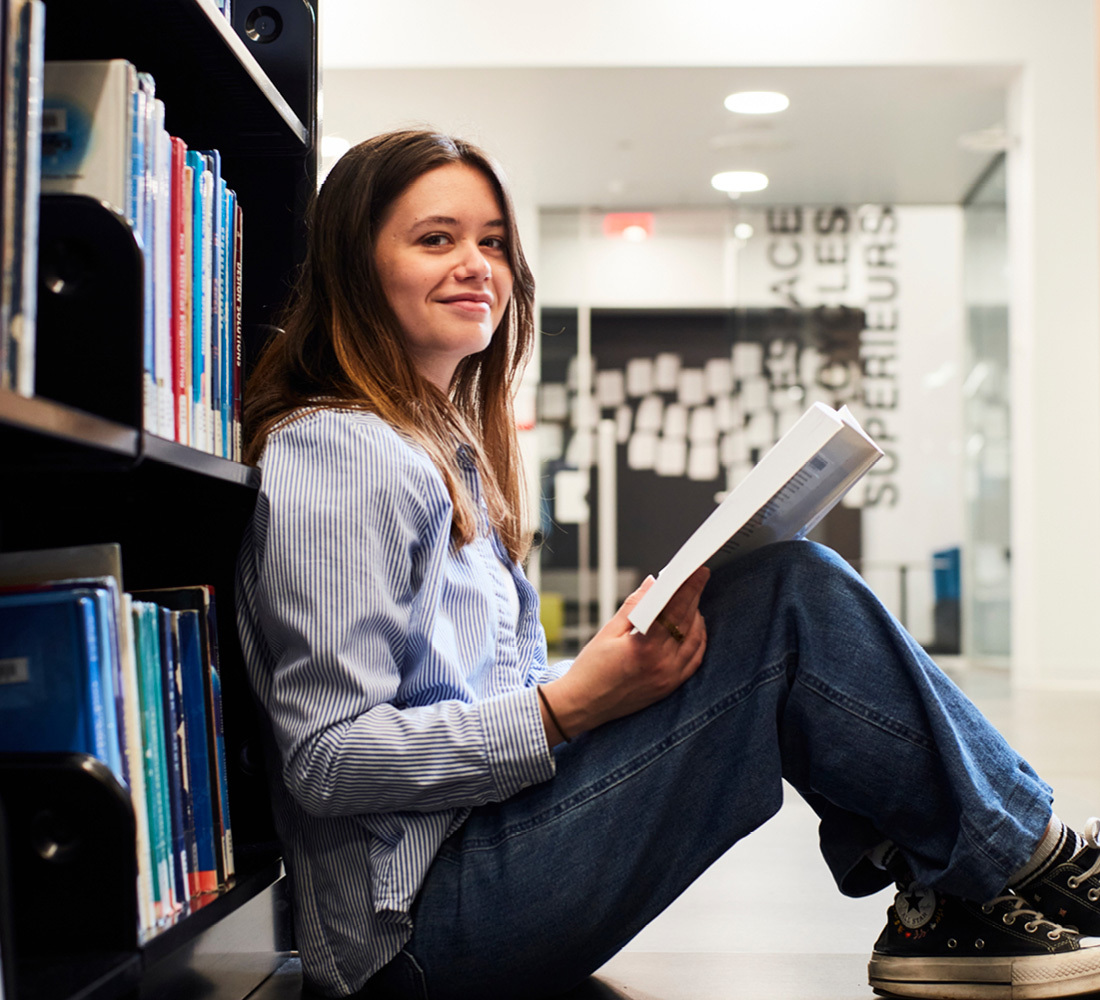 Student studies in the library, engrossed in technology literature.