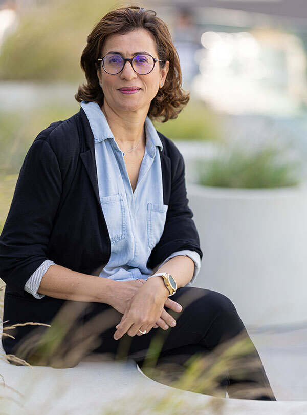 Professional female academic in smart casual attire sitting outdoors.