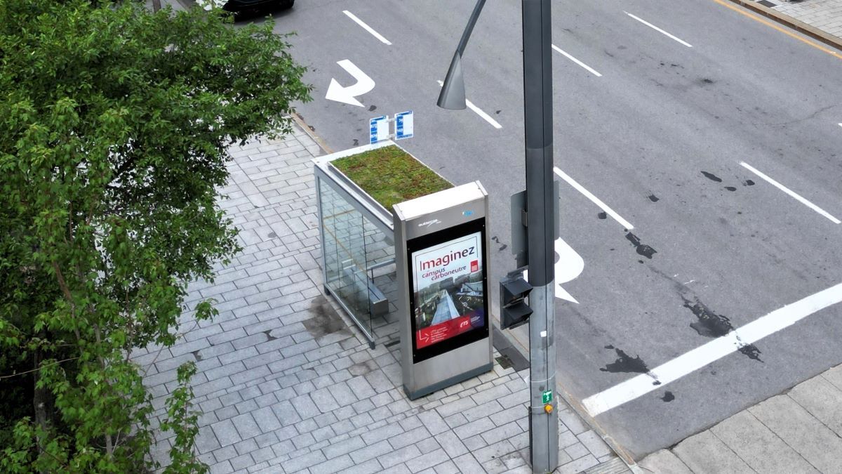 High-tech university bus stop with digital display and green roof.