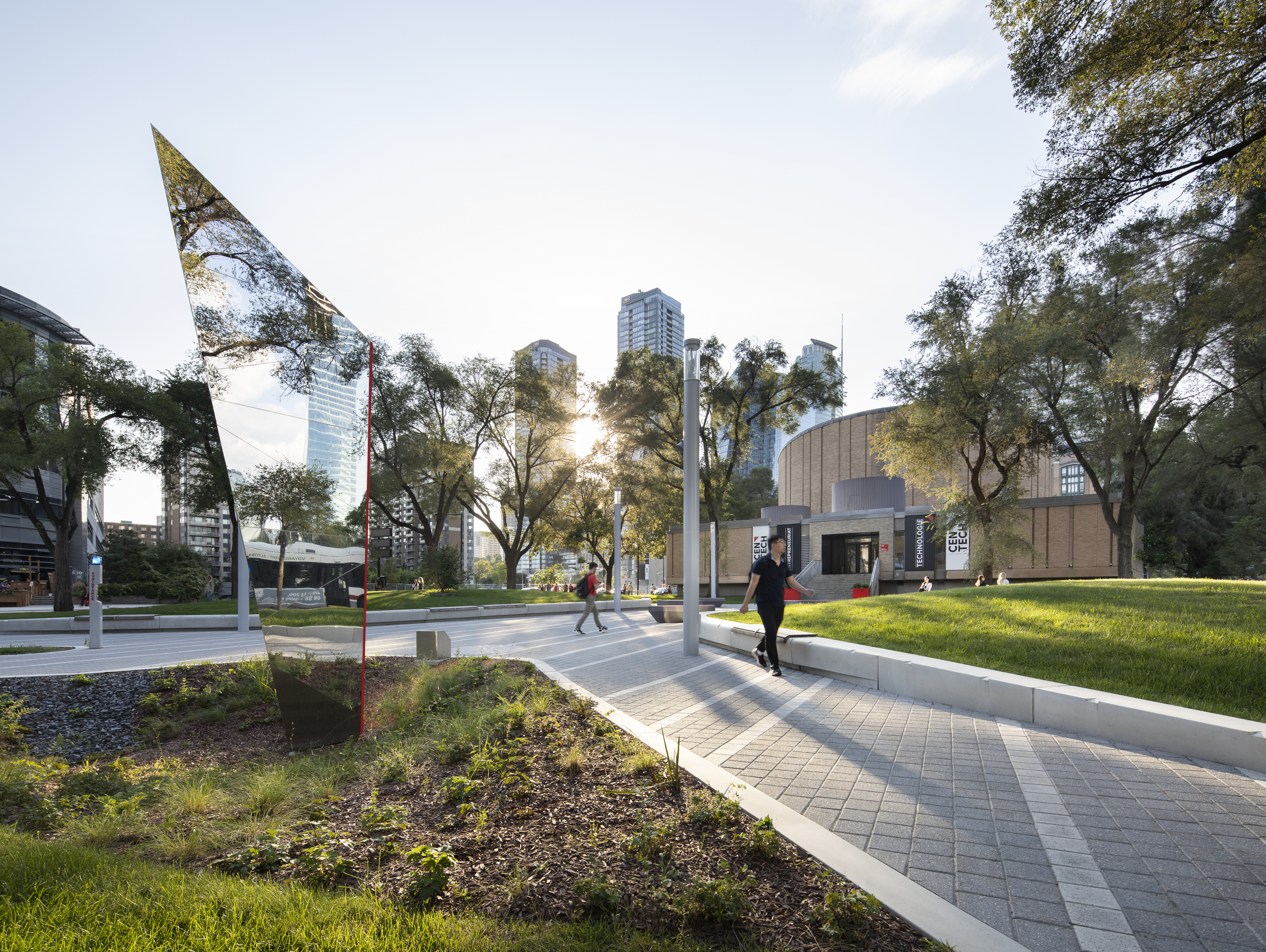 Campus moderne avec espaces verts, étudiants et installations urbaines.