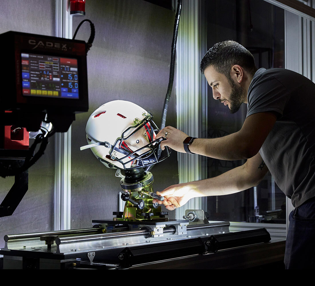 Engineer tests helmet safety with advanced equipment in a tech lab.