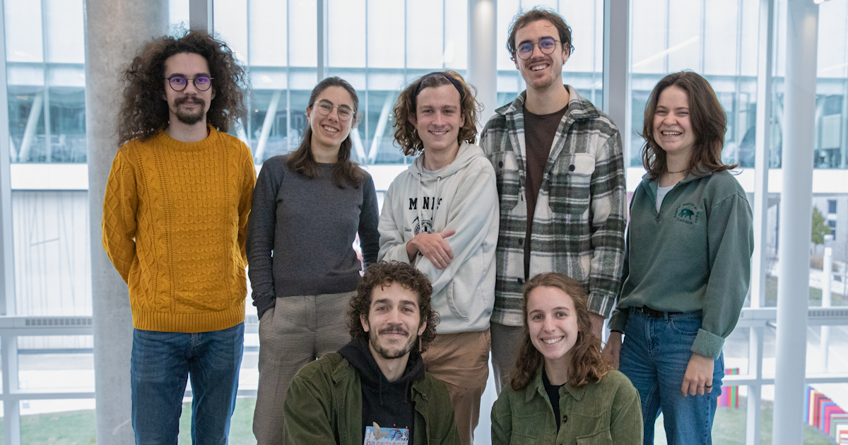 Groupe d'étudiants souriants dans un hall universitaire.