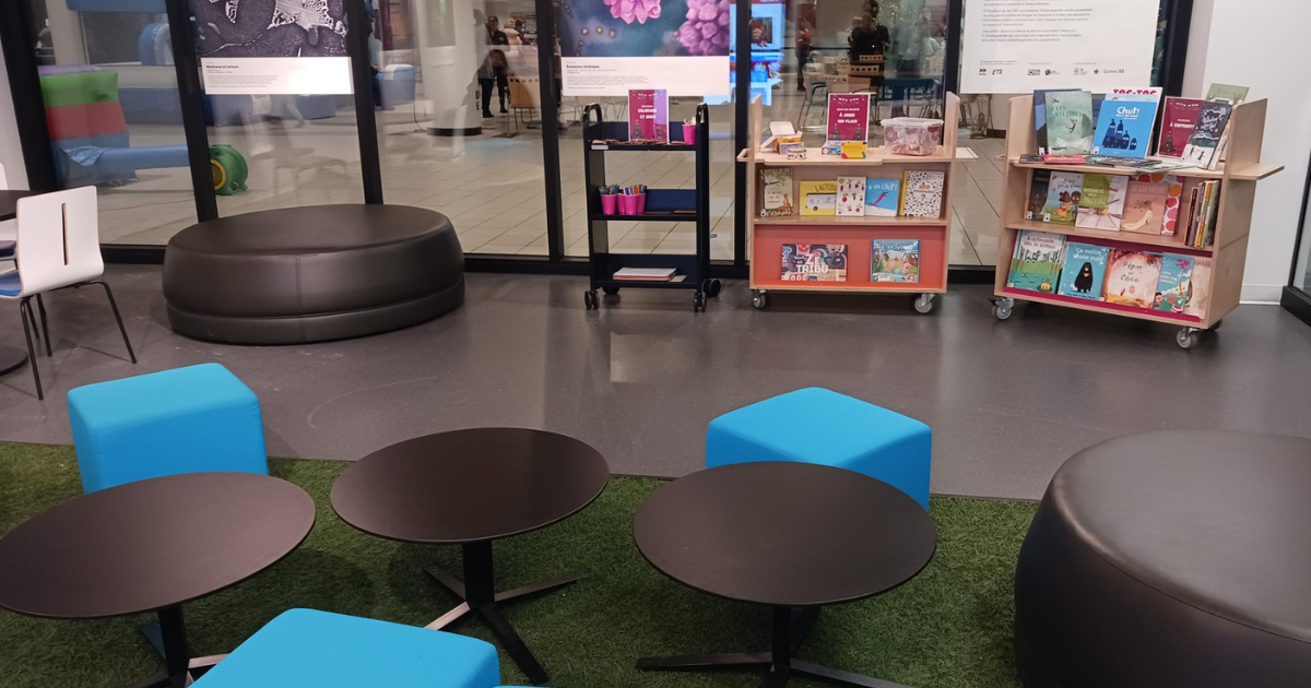 Espace détente avec sièges colorés, tables basses et bibliothèque mobile.