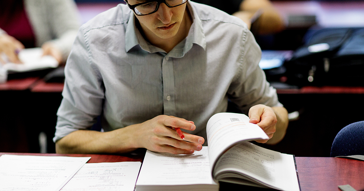 Étudiant en pleine concentration, lisant un manuel académique.